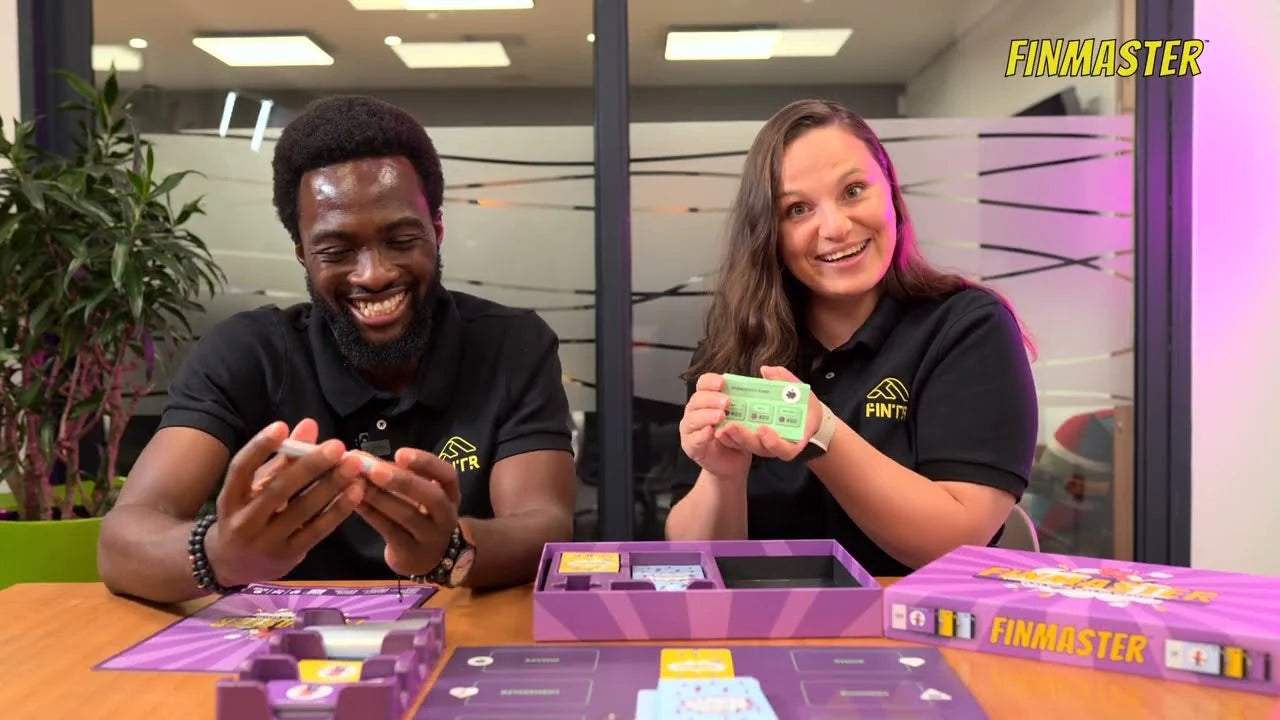 Two people smiling at a table with the FinMaster board game